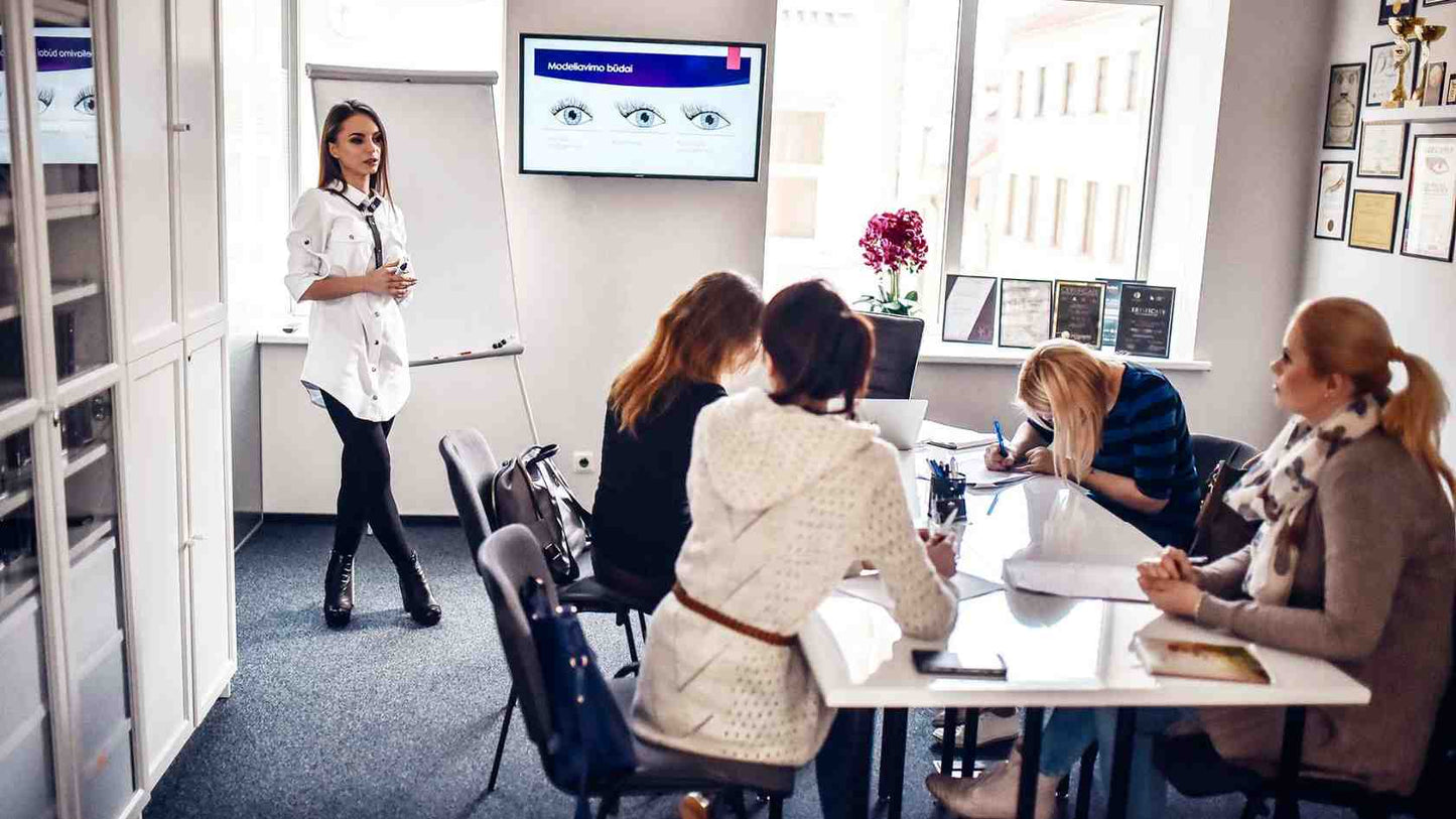 Mokytpja prie lentos desto blakstienu priauginimo kursu teorija keturios mokines prie stalo klausosi uzsirasineja