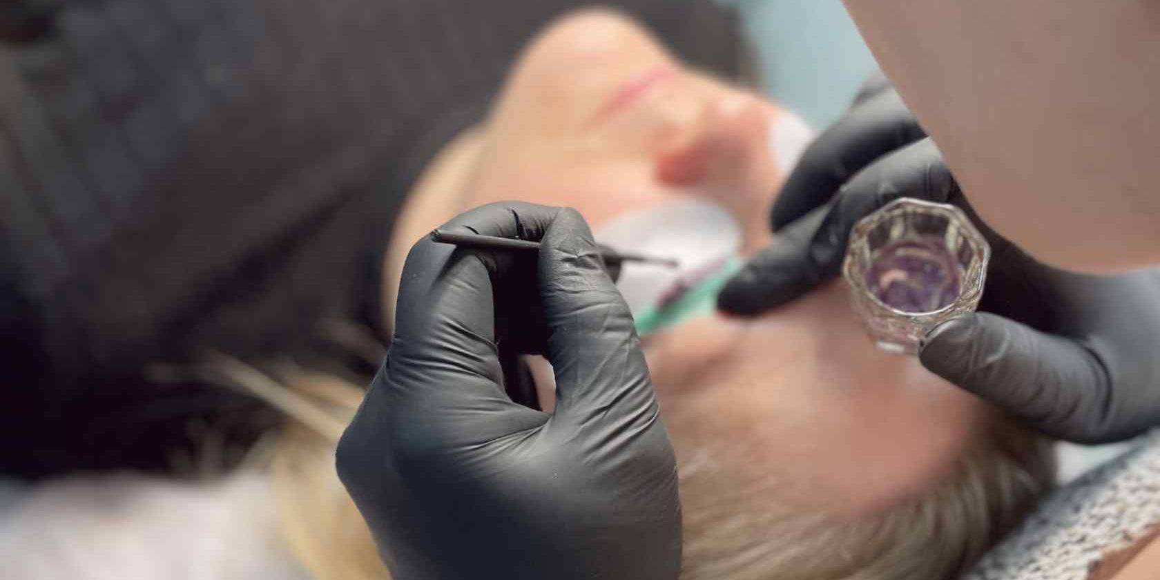 Mokinė su mikrošepetėliu tepa blakstienų dažus ant blakstienų